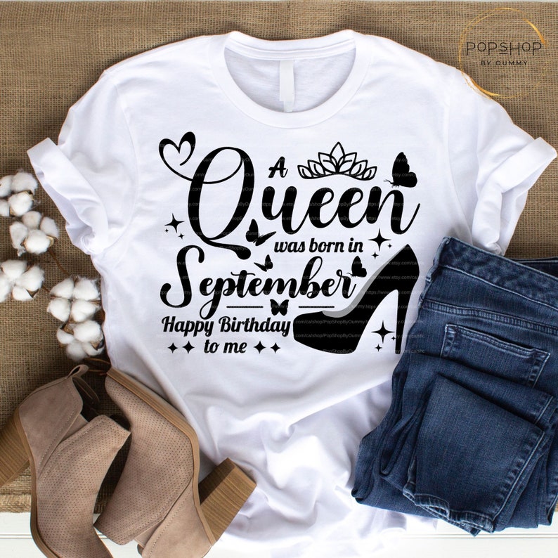 May include: White t-shirt with black text that reads "A Queen was born in September Happy Birthday to me". The text is surrounded by small black butterflies, hearts, and stars. A black high heel shoe is on the bottom right of the shirt.