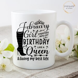 May include: White ceramic mug with a black design that says "February Girl Birthday Like a Queen & living my best life". The design also includes a crown, a heart, an arrow, and a boot.