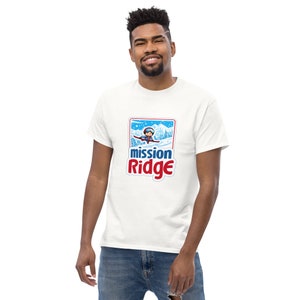 May include: White t-shirt with a blue and red logo that says "mission Ridge". The logo features a cartoon skier in a winter scene.