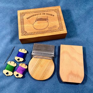Könnte beinhalten: Ein Speedweve 28 Haken Webset aus Holz. Das Set enthält eine Box mit dem Text "Speedweve 28 hooks", ein Webwerkzeug, eine Holzspule, eine Nadel und drei Garnrollen in Blau, Grün und Lila.