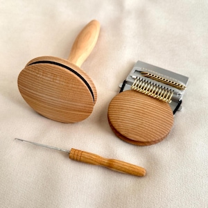 Peut inclure: Un ensemble d'outils pour le travail des fibres comprenant une cardeuse à main ronde en bois avec manche, une plus petite cardeuse ronde en bois avec un peigne métallique à dents dorées et un crochet fin en métal avec un manche en bois.