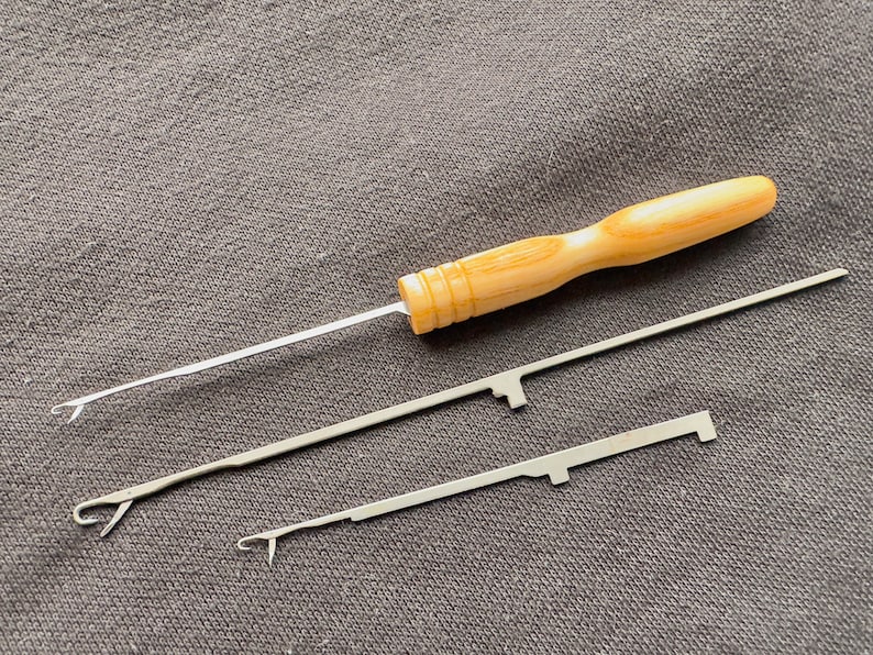 May include: Three knitting needles with wooden handles. The needles are made of metal and have a pointed tip. The handles are made of wood and have a smooth finish.