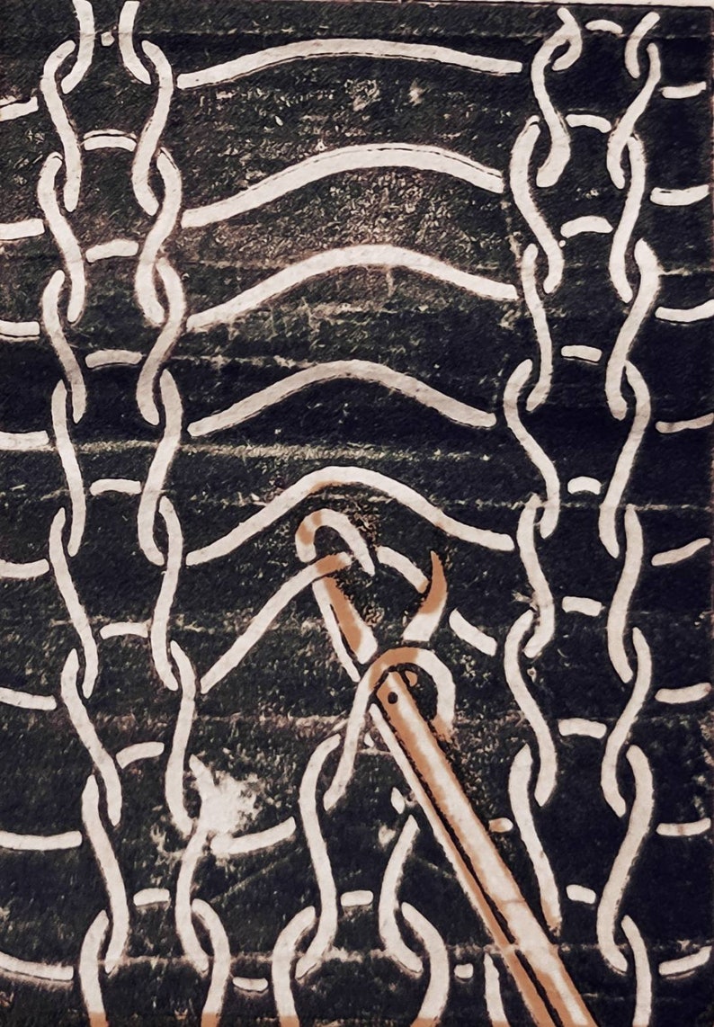 May include: A close-up of a knitting needle being used to create a chain stitch in a white yarn. The yarn is being worked into a pattern of interlocking loops.