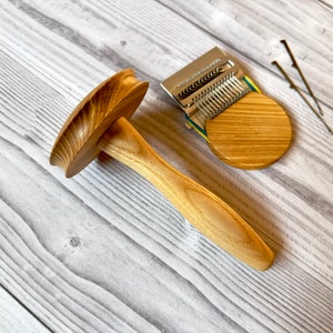 Puede incluir: Un enhebrador de lana de madera con una base redonda y un mango. El enhebrador est&aacute; hecho de madera marr&oacute;n claro y tiene un acabado natural. Tambi&eacute;n hay un enhebrador de lana de metal con una base de madera.