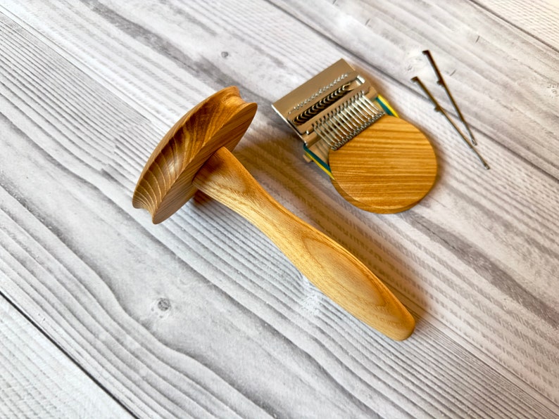 Puede incluir: Un enhebrador de lana de madera con una base redonda y un mango. El enhebrador est&aacute; hecho de madera marr&oacute;n claro y tiene un acabado natural. Tambi&eacute;n hay un enhebrador de lana de metal con una base de madera.