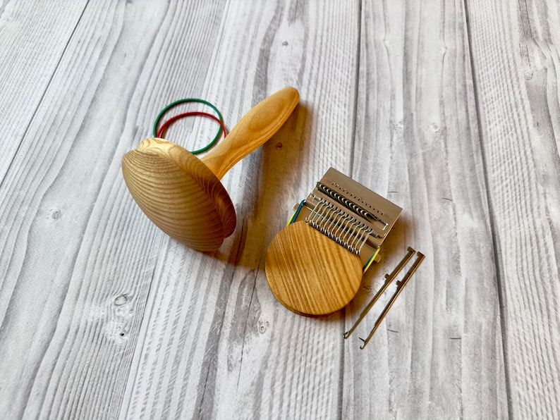 Puede incluir: Un telar de punto de madera con una base circular y una barra de agujas de metal. El telar viene acompa&ntilde;ado de dos agujas de tejer de metal y una banda el&aacute;stica.