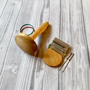Puede incluir: Un telar de punto de madera con una base circular y un conjunto de agujas de metal. El telar viene acompa&ntilde;ado de dos clavijas de madera y un juego de gomas el&aacute;sticas.