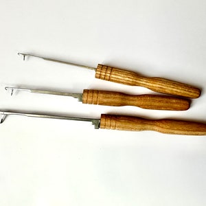 Pu&ograve; includere: Tre uncinetti con manici in legno e punte in metallo. Gli uncinetti sono di diverse dimensioni.