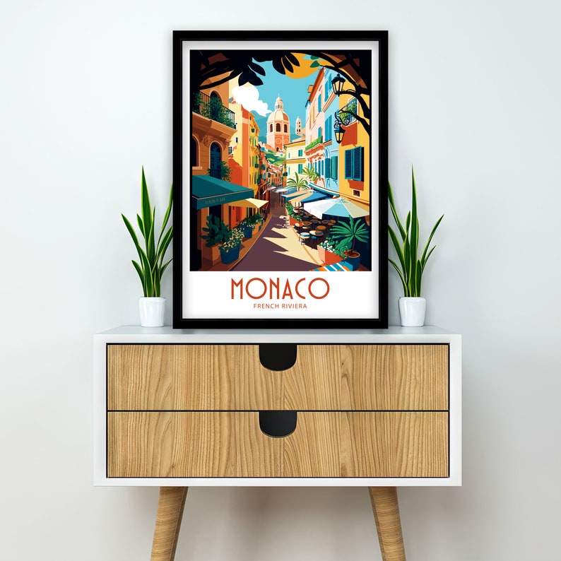 May include: A colorful illustration of a street scene in Monaco, France. The image features a narrow street lined with colorful buildings, palm trees, and people walking. The text "MONACO FRENCH RIVIERA" is printed at the bottom of the image.