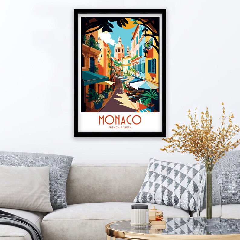 May include: A colorful illustration of a street scene in Monaco, France. The image features a narrow street lined with colorful buildings, palm trees, and outdoor cafes. The text "MONACO FRENCH RIVIERA" is displayed at the bottom of the image.