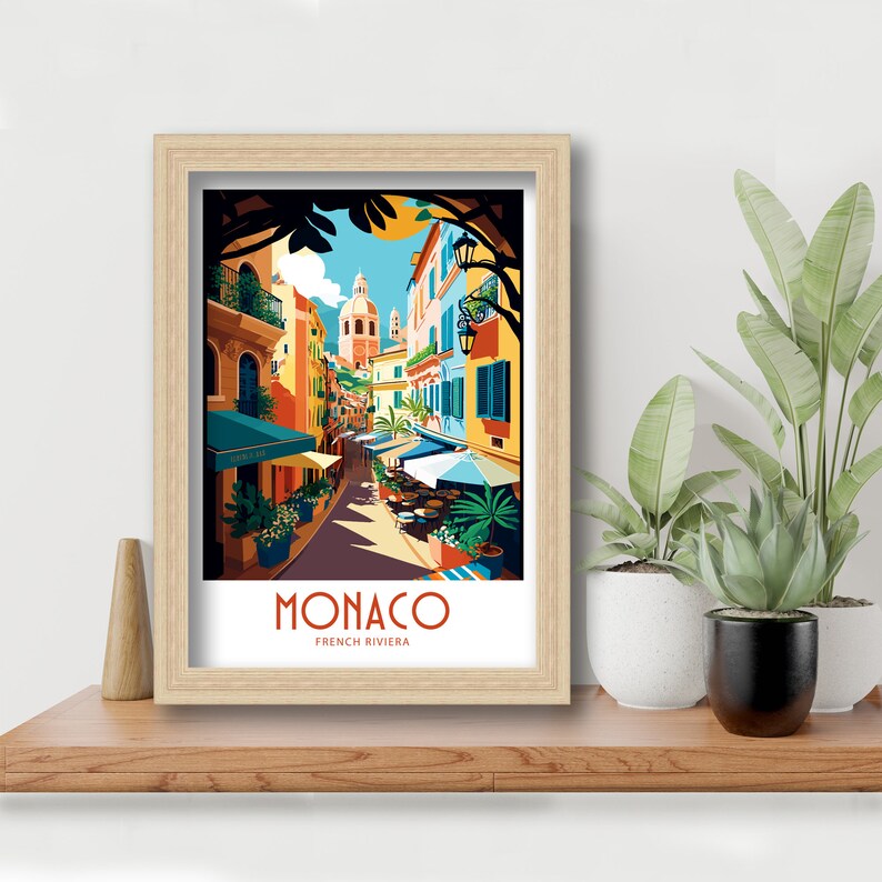 May include: A colorful illustration of a street scene in Monaco, France. The image features a narrow street lined with colorful buildings, palm trees, and outdoor cafes. The text "MONACO FRENCH RIVIERA" is displayed at the bottom of the image.