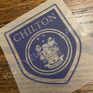 May include: A blue and silver shield-shaped sticker with the word "CHILTON" at the top. The center features a crest with the words "CARPE DIEM" and "CHILTON". The sticker is on a clear backing.