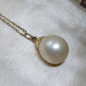 May include: A white pearl pendant necklace with a gold chain. The pearl is large and round, and the chain is delicate.