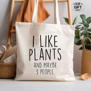 May include: A white canvas tote bag with black text that reads "I like plants and maybe 3 people."