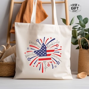 May include: A white canvas tote bag with a red, white, and blue star-shaped firework design. The design includes the words "fireworks", "4th of July", "family", "ice cream", and "freedom".