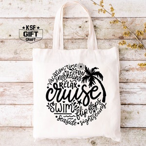 May include: White canvas tote bag with a black design that says "vacation time, snorkeling, fun, relax, cruise, swim, flip flops, seaside, sightseeing". The design is in a circle with a palm tree in the center.