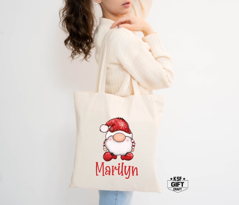 May include: A white canvas tote bag with red and white gnome illustration and the name "Marilyn" printed on the front.