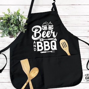 May include: Black apron with two pockets and white text that reads "Beer and BBQ" with a graphic of two beer mugs and grilling tools.