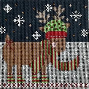 May include: A brown reindeer illustration wearing a green and red hat, scarf, and socks. The reindeer has antlers and is set against a dark blue background with snowflakes. The image is a needlepoint design.