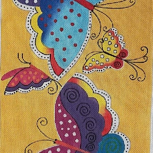 May include: A vibrant butterfly design against a yellow backdrop. The butterflies display detailed patterns in blue, purple, red, and yellow, with white and black detailing. The artwork is likely a needlepoint or cross-stitch piece.