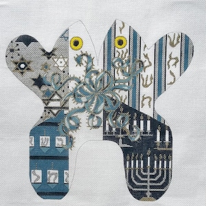 May include: A decorative canvas featuring a stylized, symmetrical design with a patchwork of patterns. The design incorporates blue, gray, and white hues, with elements like stars, stripes, and a menorah. A central teal floral motif adds detail.