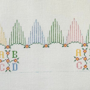 May include: A cross-stitch pattern featuring five colourful trees and the letters A, B, C, and D arranged in a floral design.