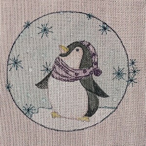 Könnte beinhalten: Eine Stickvorlage mit einem kreisförmigen Motiv eines schwarz-weißen Pinguins, der einen violetten gemusterten Schal und eine passende Mütze trägt. Der Pinguin steht auf einem weißen Schneeboden, umgeben von dunkelblauen gestickten Schneeflocken.