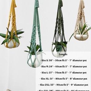 May include: Four macrame plant hangers in yellow, teal, olive green, and beige, each holding a white ceramic pot with a green plant. The hangers are suspended from metal hooks. The image includes size details: 20"-120" length.