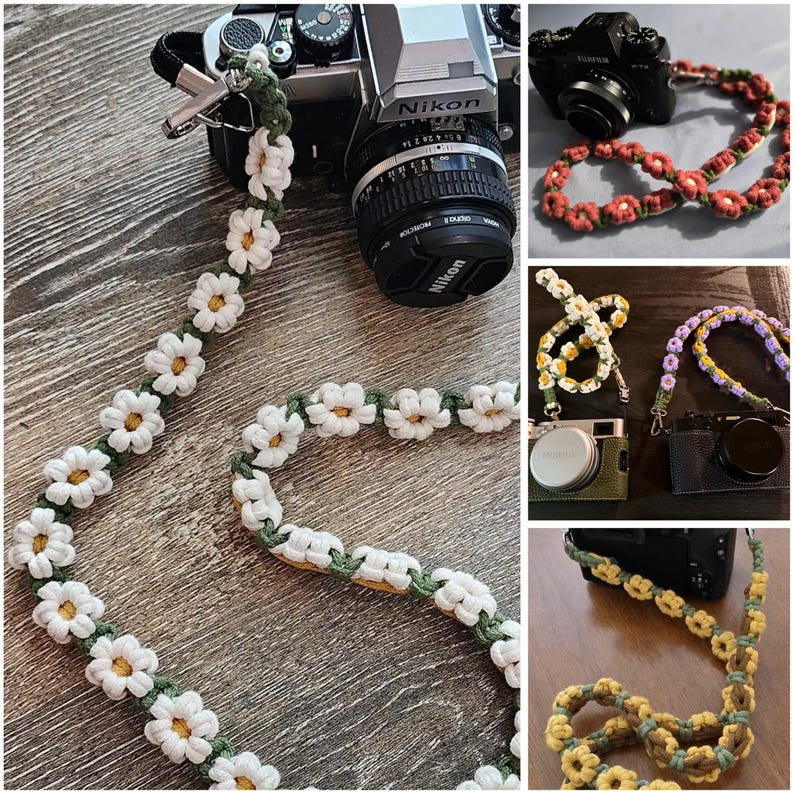 May include: A camera strap featuring a repeating pattern of crocheted white daisy flowers with yellow centers, connected by a green cord. The strap includes metal swivel clips at each end for attachment to a camera body, showcasing a floral design.