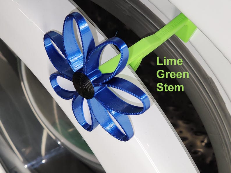 May include: A blue 3D printed flower with a black center, attached to a lime green stem. The stem is bent at a 90-degree angle.  The flower and stem are attached to a white surface.