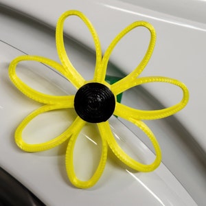 May include: A yellow flower-shaped object with a black center. The object is made of plastic and has a textured surface.