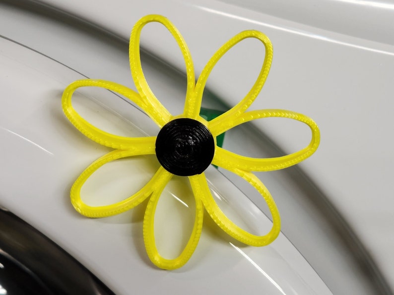 May include: A yellow flower-shaped object with a black center. The object is made of plastic and has a textured surface.