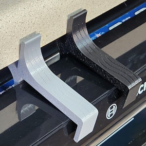 May include: Two 3D printed dishwasher door handles, one gray and one black, are attached to a black dishwasher. The dishwasher has a digital display with the word "Delay" and the Bosch logo.