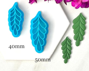 May include: Two blue leaf-shaped polymer clay cutters, one 1.6 inches and the other 2 inches long, next to two green leaf-shaped clay pieces. The image includes a sprig of purple flowers and the measurements 40mm and 50mm.