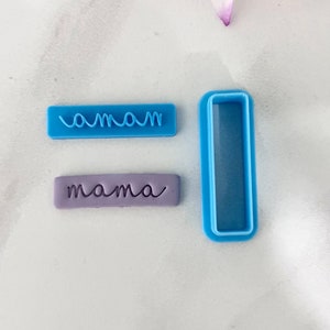 May include: Two blue plastic cookie cutters, one with the word "mama" and the other a rectangle. A purple fondant cutout with the word "mama" is also shown.