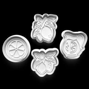 May include: Four white cookie cutters in the shape of lemons and a pitcher of lemonade. The cutters include a lemon slice, two lemon and leaf designs, and a pitcher with a lemon slice. The cutters are on a black background.
