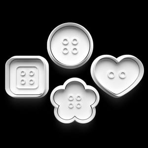 May include: Four white button-shaped cookie cutters on a black background. The shapes include a square, a circle, a flower, and a heart. Each cutter has a button design with four holes.