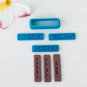 May include: A set of blue and brown polymer clay stamps for baking and crafting. The stamps feature the words "mom", "mamma", and "mama" in a handwritten font. There is also a blue rectangle stamp with a wavy line design.