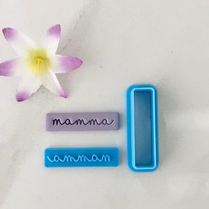 May include: Two blue plastic cookie cutters, one with the word "mamma" and the other with the word "ammam". A purple cookie cutter with the word "mamma" is also included.