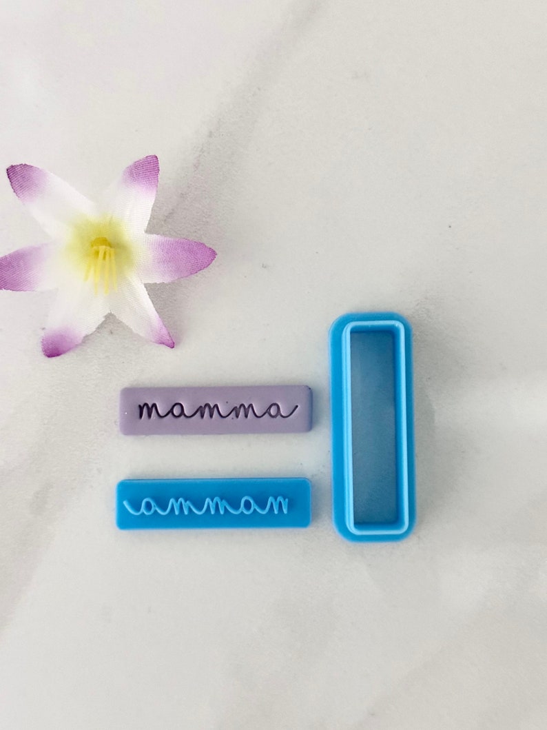 May include: Two blue plastic cookie cutters, one with the word "mamma" and the other with the word "ammam". A purple cookie cutter with the word "mamma" is also included.