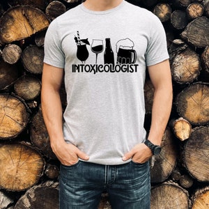 May include: A gray t-shirt with a black graphic of four different drinks and the text "INTOXICOLOGIST".