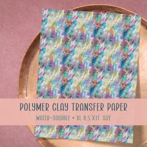 Puede incluir: Papel de transferencia para arcilla polimérica con un diseño abstracto colorido en tonos azules, morados, verdes y naranjas. El papel es soluble en agua y XL, mide 21,6 x 27,9 cm. El texto "POLYMER CLAY TRANSFER PAPER" está impreso.