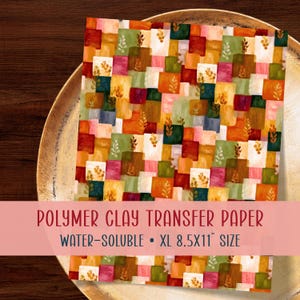 May include: A rectangular sheet of polymer clay transfer paper featuring a grid of multicoloured squares in shades of red, orange, yellow, green, and white, accented with small leaf patterns. The text reads POLYMER CLAY TRANSFER PAPER WATER-SOLUBLE XL 21.6X27.9 CM SIZE.