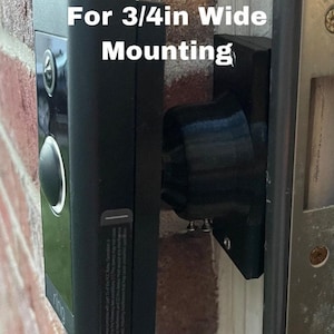 May include: A black Ring Wired 2021 video doorbell mounted with a 0-35 degree angle adapter and a narrow adapter for 1.9cm wide mounting. The device features a camera lens and a circular button, with text overlay describing the mounting hardware.