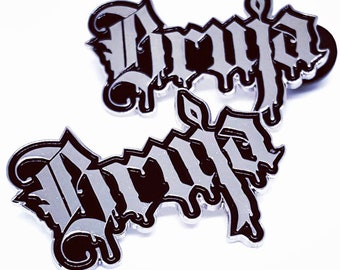 May include: Two silver-colored metal pins with the word "Drip" written in black lettering. The lettering is stylized and dripping, giving the word a 3D effect.