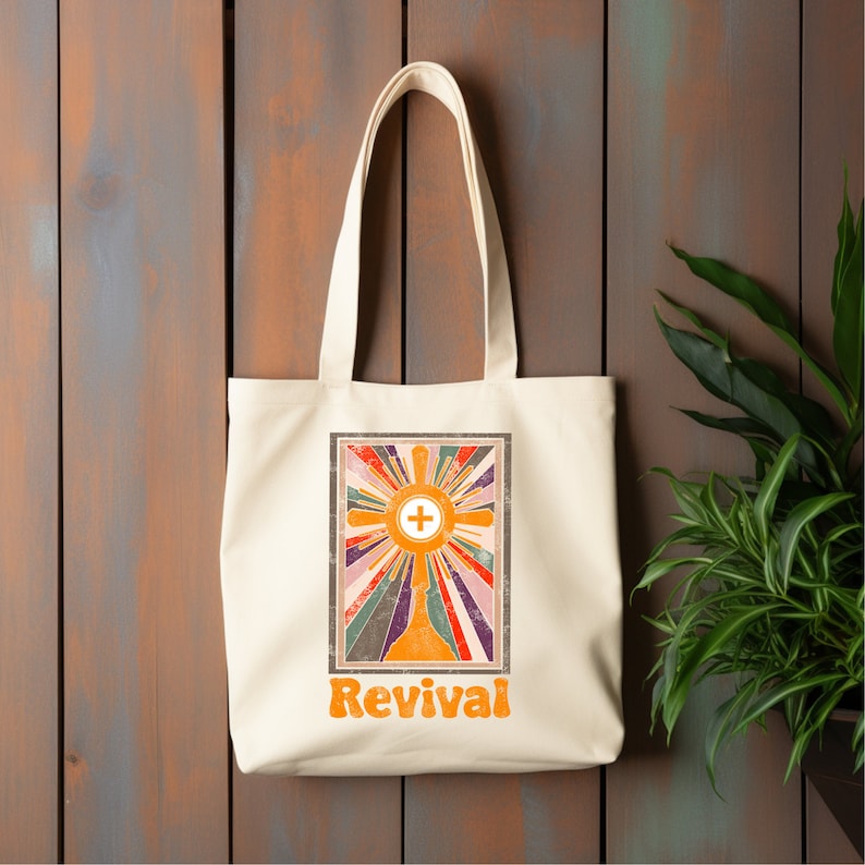 May include: A white tote bag with a retro-style design featuring a cross in a sunburst with the word "Revival" in orange letters.