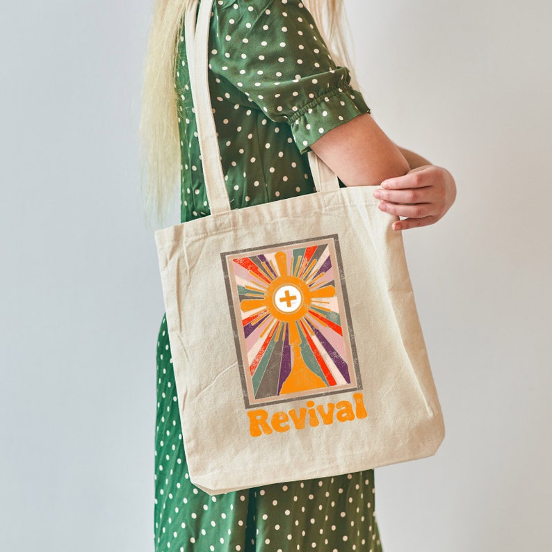 May include: A beige tote bag with a colorful retro design featuring a cross and the word "Revival".