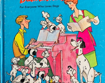 May include: A vintage children's book cover featuring a cartoon illustration of a family of Dalmatian dogs singing with a human couple. The book title is "One Hundred and One Dalmatians" and the text "For Everyone Who Loves Dogs" is below the title. The book cover is blue with a white border and the text is in black.