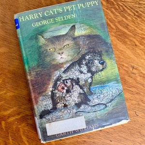 May include: A book cover with a green background featuring a cat and a dog. The title of the book is "Harry Cat's Pet Puppy" by George Selden. The illustrator is Garth Williams.