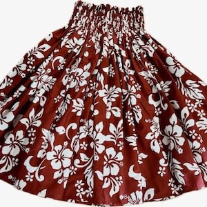 Op de afbeelding: Een bruine rok met een wit bloemenpatroon. De rok heeft een gerimpelde tailleband en een volle vorm. Het bloemmotief omvat hibiscusbloemen en bladeren, wat een tropische uitstraling cre&euml;ert. Perfect voor de zomer.
